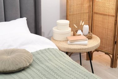 Yatağın yanında kitap ve dekor olan yan masa.