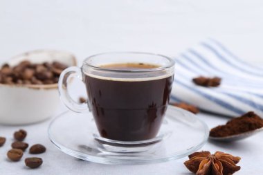Bir fincan aromatik kahve, fasulye ve yıldız anason beyaz masada, yakın plan.