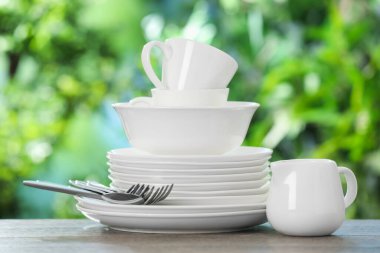 Ahşap masada, bulanık yeşil arka planda farklı temiz tabaklar.