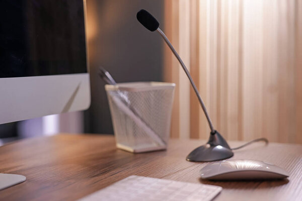 Микрофон и компьютер на деревянном столе в помещении