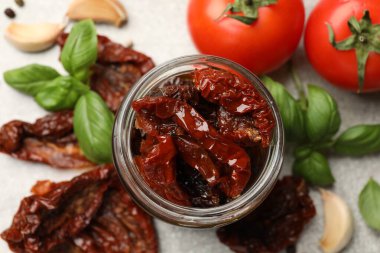 Lezzetli güneşte kurutulmuş domatesler, taze sebzeler ve baharatlar gri masada, düz yerde.