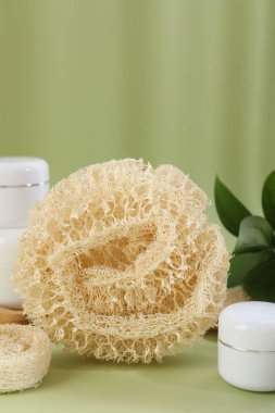 Zeytin arka planında banyo süngeri ve kozmetik ürünlerin kavanozları, yakın plan