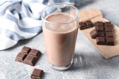 Lezzetli çikolatalı süt cam ve parçalar gri masada, yakın plan.