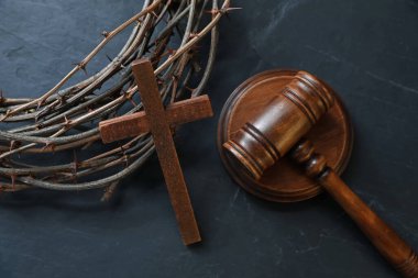 Yargıç tokmağı, dikenli taç ve tahta haç siyah masada, düz yatıyordu.