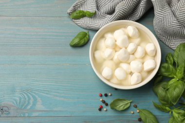 Mavi ahşap masada fesleğenli ve biberli Mozzarella peyniri topları. Metin için boşluk