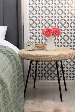 Çalar saati, kitapları ve yatağın yanında dekorasyonu olan yan masa.