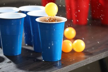 Bira pong oyunu. İçkili plastik bardaklar ve toplar ahşap masada, yakın plan. Metin için boşluk