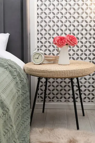 Çalar saati, kitapları ve yatağın yanında dekorasyonu olan yan masa.