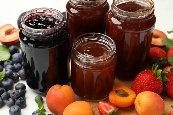 Kavanozlardaki farklı tatlı reçeller ve malzemeler masada, yakın plan.