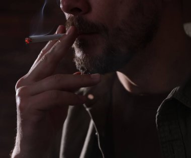 Arka planda sigara içen adam, yakın plan.