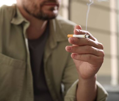Arka planda sigara içen adam, yakın plan.