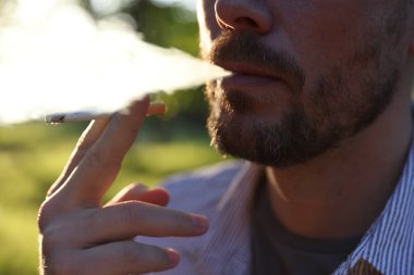 Arka planda sigara içen adam, yakın plan.