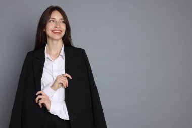 Gri arka planda takım elbiseli mutlu kadın, mesaj için boşluk