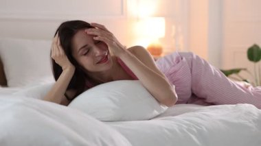 Evde yumuşak bir şilteyle yatakta uzanan bir kadın.