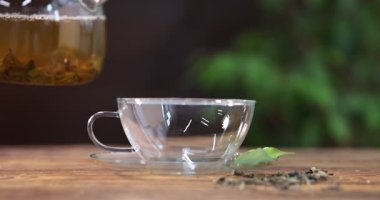 Lezzetli yeşil çayı çaydanlıktan, ahşap masaya, yakın plan fincana dök.