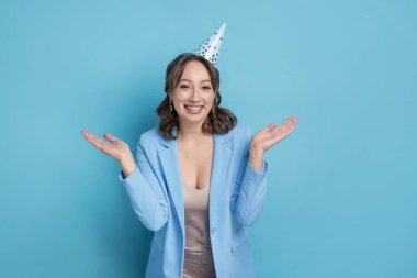 Doğum günü kutlaması. Açık mavi arka planda parti konisi olan mutlu bir kadın.