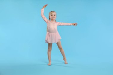 Açık mavi arka planda dans eden tatlı küçük kız.