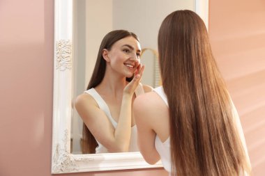 Güzel bir kadın aynada kendine bakıyor.