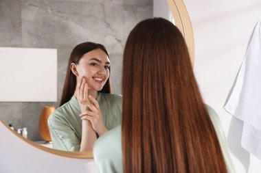 Güzel bir kadın aynada kendine bakıyor.