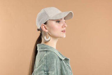Beyzbol şapkalı güzel bir kadın bej arka planda.