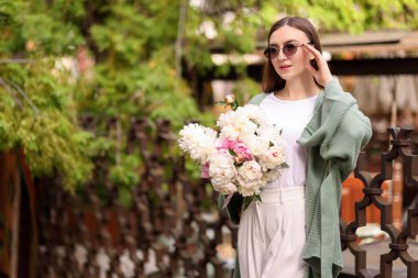 Şehir caddesinde bir buket güzel şakayığı olan çekici bir kadın. Metin için boşluk