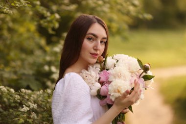 Parkta şakayık demeti olan güzel bir kadın.