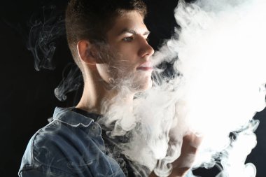 Siyah arkaplanda elektronik sigara içen adam