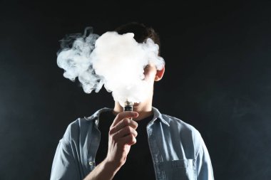 Siyah arkaplanda elektronik sigara içen adam