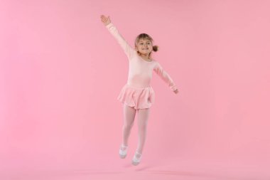 Pembe arka planda dans eden tatlı küçük kız.