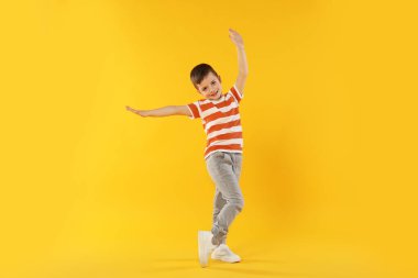 Mutlu küçük çocuk turuncu arka planda dans ediyor