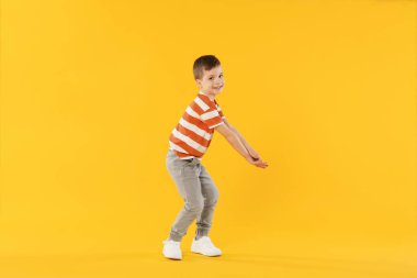 Mutlu küçük çocuk turuncu arka planda dans ediyor