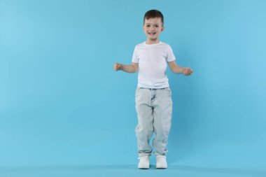Açık mavi arka planda dans eden mutlu küçük çocuk. Metin için boşluk