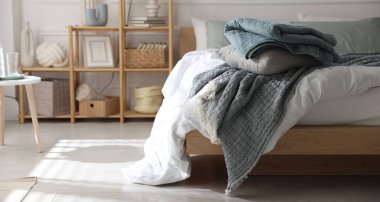 Yumuşak çarşafları olan rahat bir yatak ve şık bir odası olan bir raf. Ev tekstili