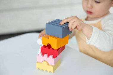 Beyaz masadaki tuğlalarla oynayan sevimli küçük çocuk, yakın plan.