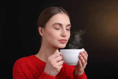 Kahverengi arka planda kahve fincanı olan bir kadın.