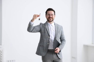 Emlakçının elinde evin anahtarı, anahtarlık ve pano var.