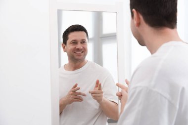 Yakışıklı adam aynada kendine bakıyor.