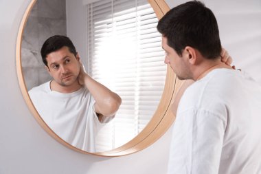 Yakışıklı adam aynada kendine bakıyor.