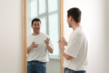 Yakışıklı adam aynada kendine bakıyor.