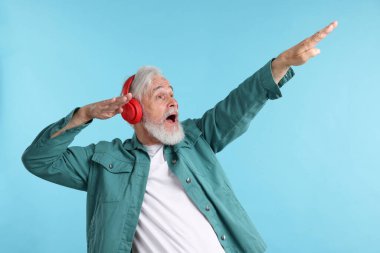 Açık mavi arka planda kulaklıklı yaşlı bir adam.