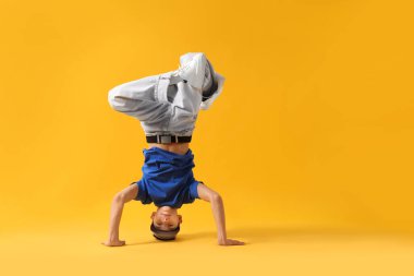 Şık giyinmiş çocuk turuncu arka planda dans ediyor, mesaj için yer var.