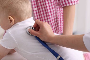 Klinikte steteskopla bebeği muayene eden çocuk doktoru.