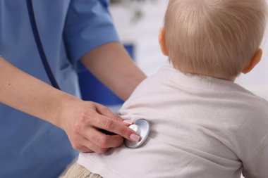 Klinikte steteskopla bebeği muayene eden çocuk doktoru.