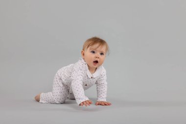 Açık gri arka planda emekleyen şirin küçük bebek, mesaj için yer