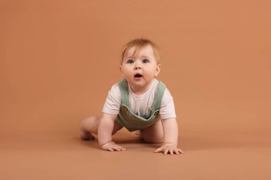 Soluk kahverengi arka planda emekleyen tatlı küçük bebek.