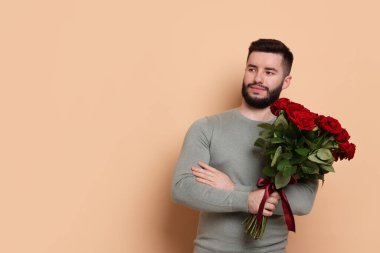 Bej arka planda kırmızı gül buketi olan mutlu adam, metin için boşluk.