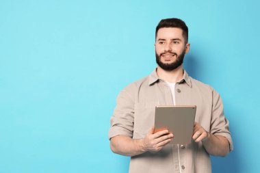 Açık mavi arkaplanda tablet kullanan adam, metin için boşluk