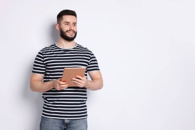 Beyaz arkaplanda tablet kullanan yakışıklı adam, metin için boşluk