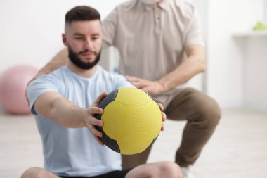 Doktor ve hasta klinikte ilaç topuyla egzersiz yapıyor.