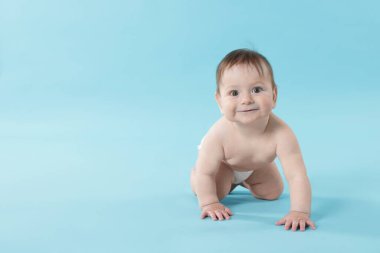 Açık mavi arka planda emekleyen şirin bir bebek. Metin için boşluk